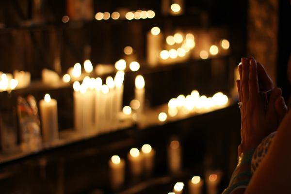 a person praying by several glowing candles